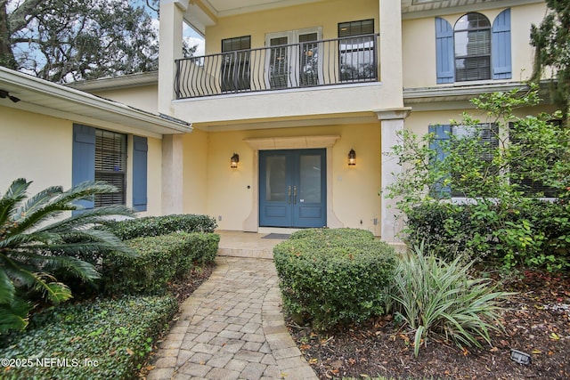 doorway to property with a balcony, stucco siding, and french doors