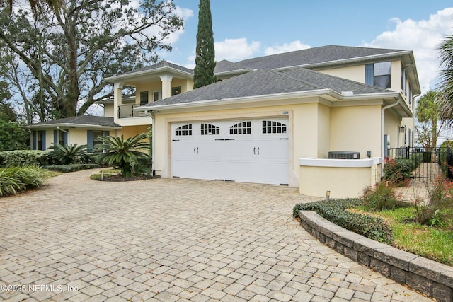 view of front of house with an attached garage, fence, roof with shingles, decorative driveway, and stucco siding