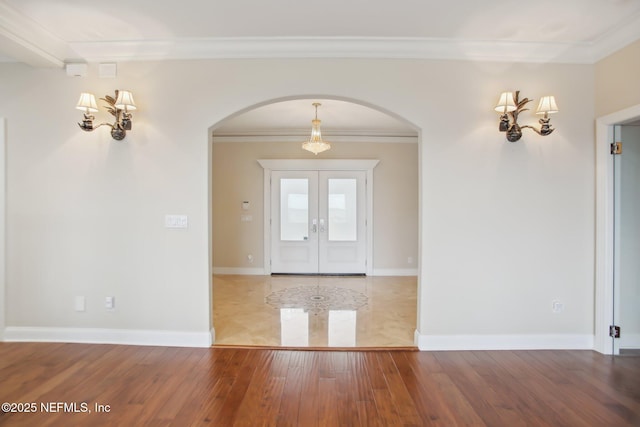 entrance foyer with arched walkways, french doors, light wood-style flooring, ornamental molding, and baseboards