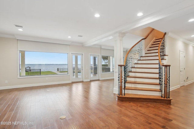 interior space featuring ornate columns, crown molding, baseboards, and wood finished floors