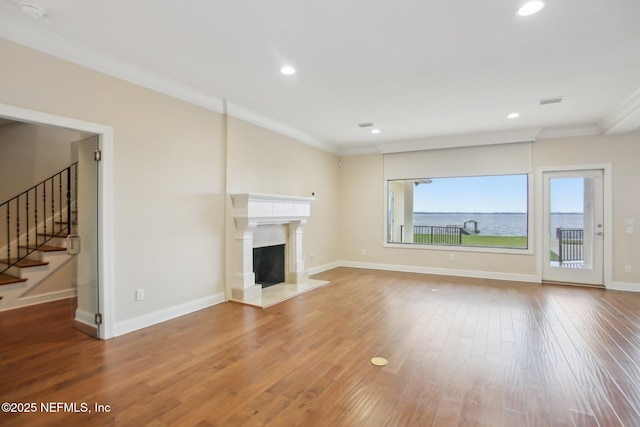 unfurnished living room featuring ornamental molding, a fireplace, baseboards, and wood finished floors