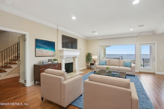 living room featuring a fireplace with flush hearth, recessed lighting, ornamental molding, and wood finished floors