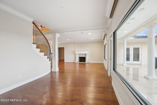 unfurnished living room featuring decorative columns, baseboards, hardwood / wood-style floors, stairs, and a fireplace