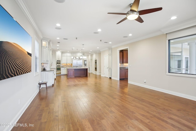 unfurnished living room featuring ornamental molding, recessed lighting, wood-type flooring, and baseboards