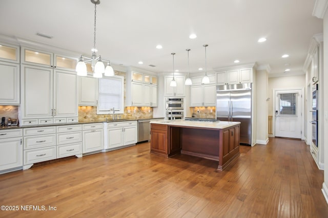 kitchen featuring stainless steel appliances, a sink, white cabinetry, decorative backsplash, and hardwood / wood-style floors