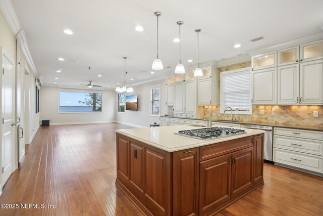 kitchen featuring crown molding, appliances with stainless steel finishes, wood finished floors, and decorative backsplash