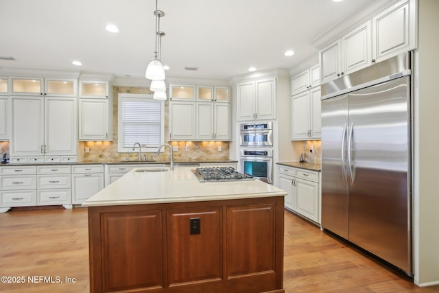 kitchen featuring stainless steel appliances, light wood-type flooring, white cabinetry, and a sink