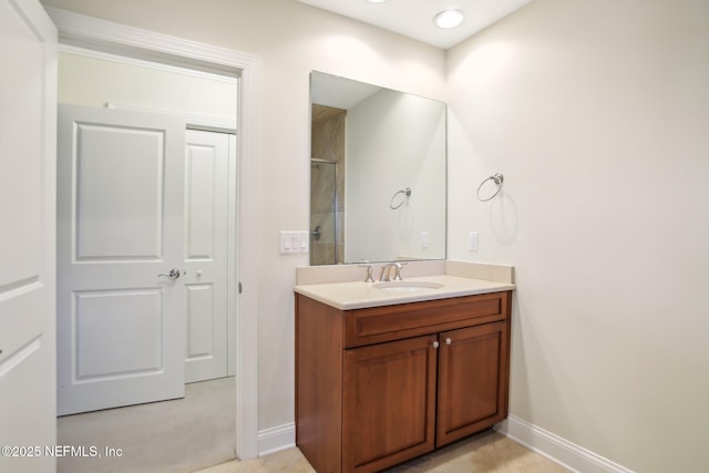 bathroom with walk in shower, vanity, and baseboards