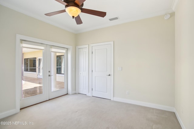 empty room featuring visible vents, baseboards, french doors, carpet, and crown molding