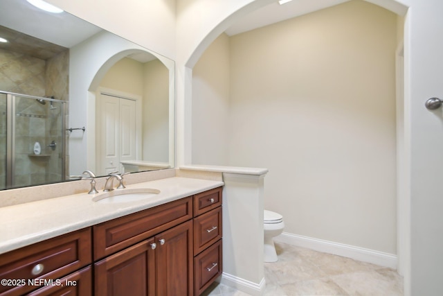 full bath with a stall shower, baseboards, vanity, and toilet