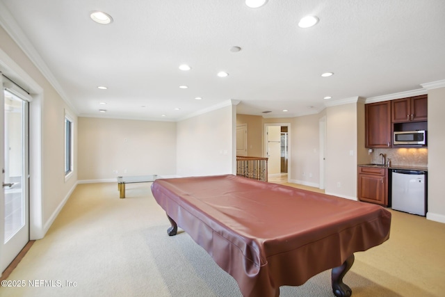 recreation room featuring a sink, baseboards, crown molding, and light colored carpet