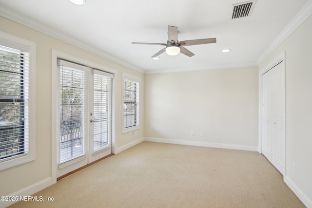 unfurnished room with light carpet, baseboards, visible vents, and crown molding