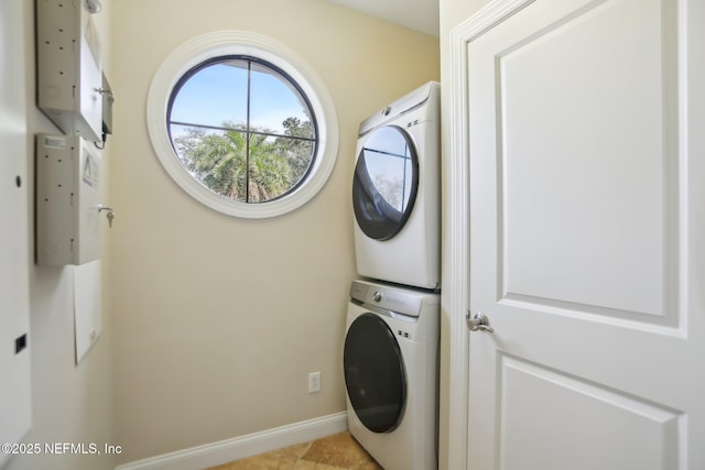 laundry room with stacked washing maching and dryer, baseboards, and laundry area