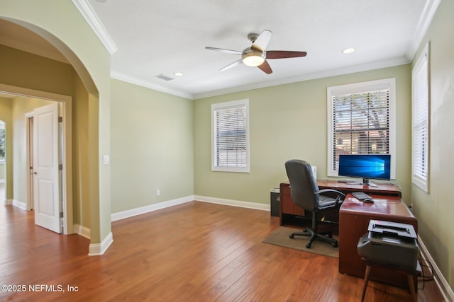 office space featuring arched walkways, wood-type flooring, visible vents, ornamental molding, and baseboards