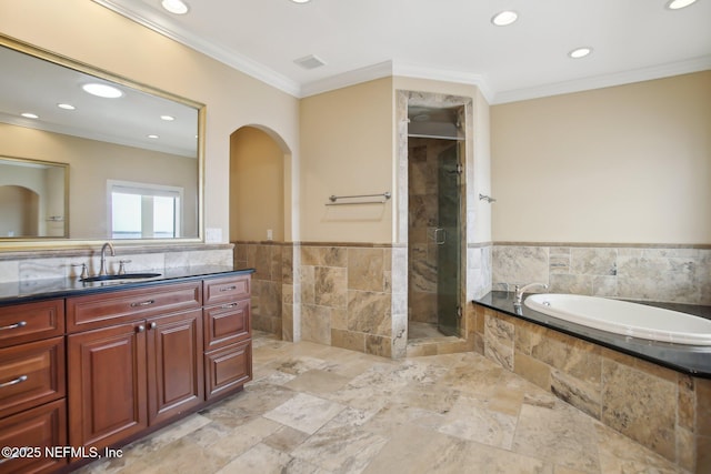 bathroom with a bath, a stall shower, tile walls, and crown molding