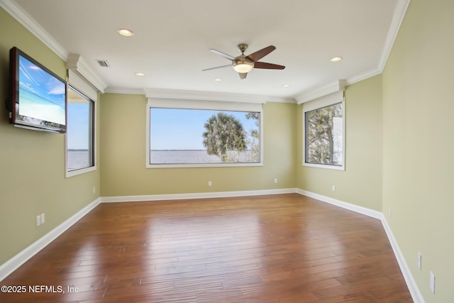 empty room with baseboards, wood-type flooring, visible vents, and crown molding