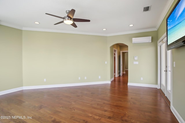 empty room featuring arched walkways, dark wood-style flooring, visible vents, baseboards, and a wall mounted air conditioner