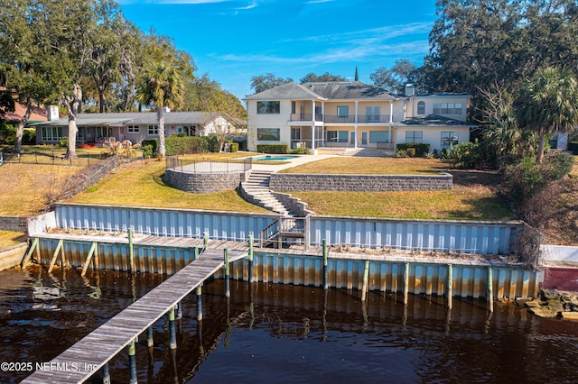 view of dock with a water view, a lawn, a patio area, a balcony, and fence private yard