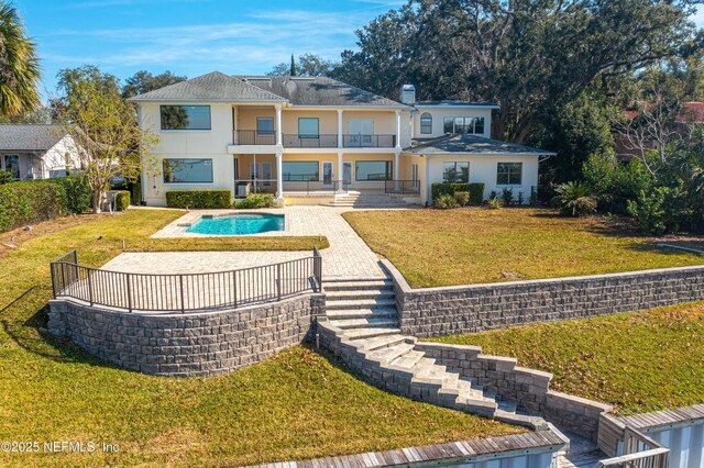 rear view of house featuring a fenced in pool, a patio, stucco siding, a lawn, and a balcony