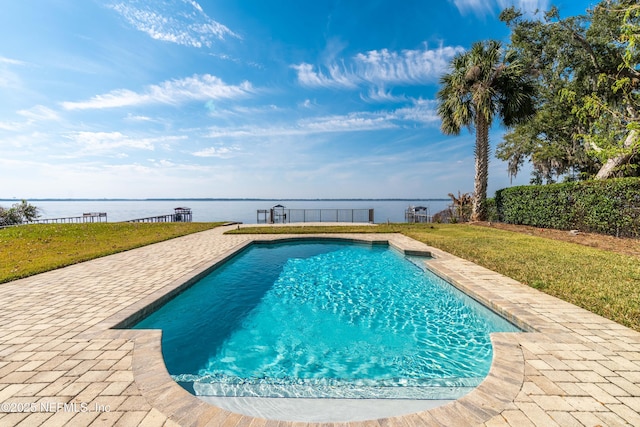 pool featuring a patio area, a water view, and a yard