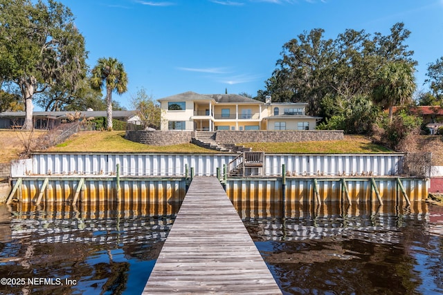 view of dock featuring a yard, stairway, a water view, and a balcony