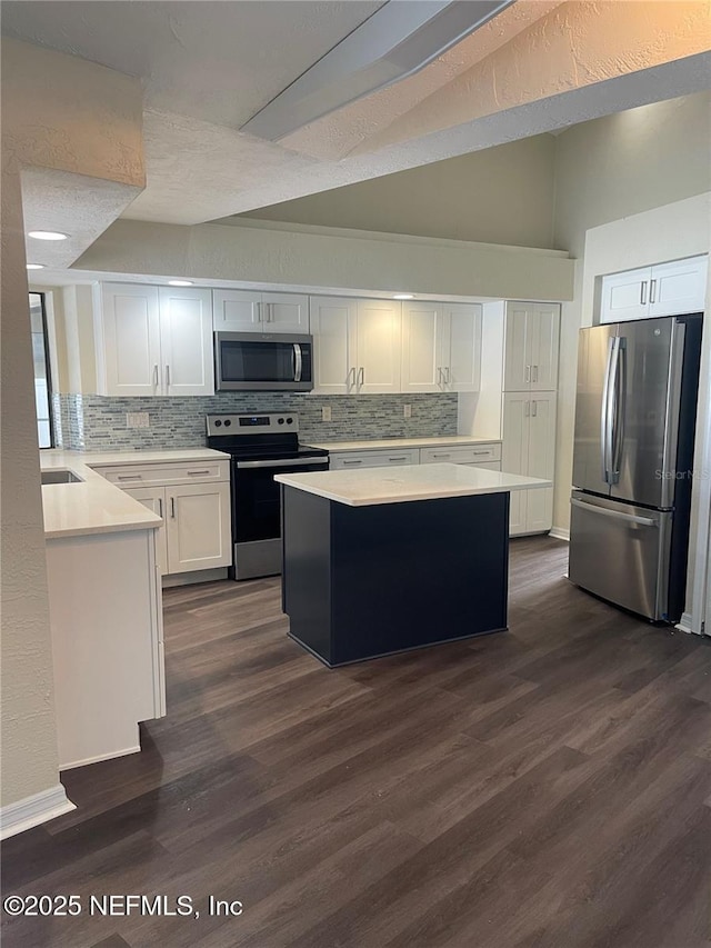 kitchen with dark wood-style floors, a center island, light countertops, appliances with stainless steel finishes, and white cabinetry