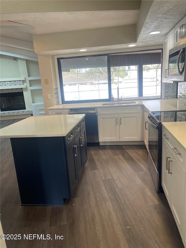 kitchen featuring appliances with stainless steel finishes, white cabinetry, a sink, and dark wood-type flooring