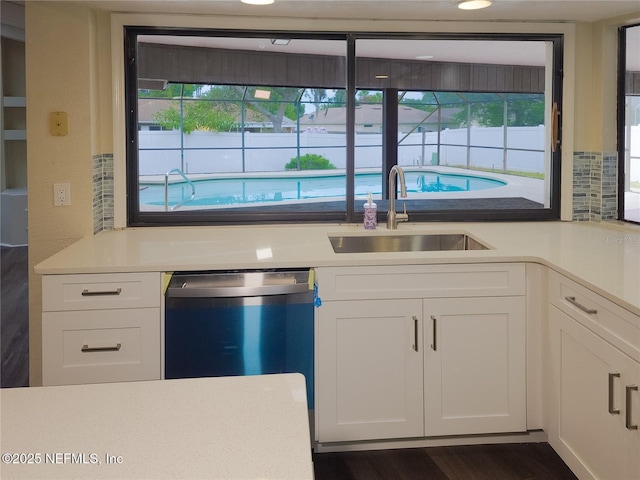 kitchen with decorative backsplash, dishwasher, light countertops, white cabinetry, and a sink