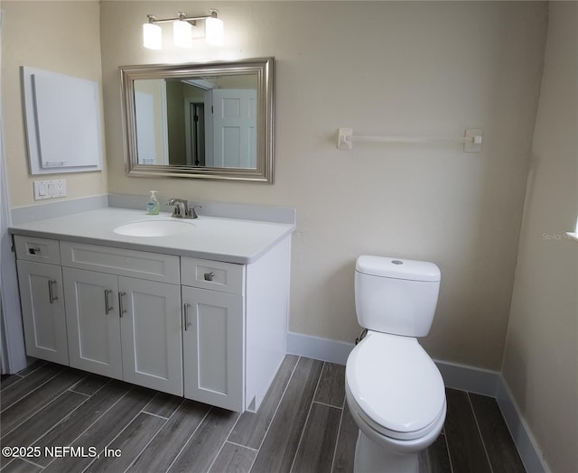 bathroom with wood tiled floor, toilet, vanity, and baseboards