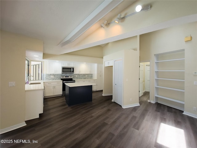 kitchen with lofted ceiling, light countertops, appliances with stainless steel finishes, white cabinets, and a sink