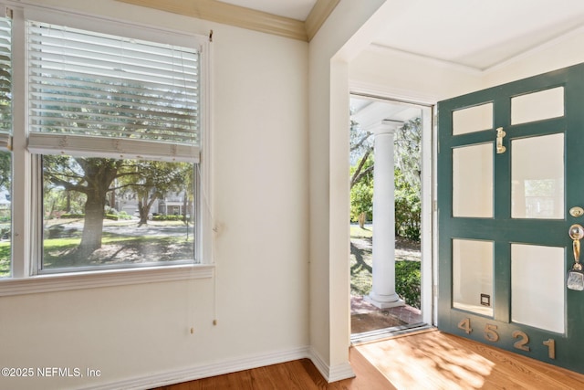 entrance foyer with ornate columns, crown molding, baseboards, and wood finished floors