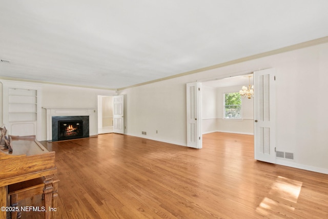 unfurnished living room featuring light wood-type flooring, baseboards, visible vents, and a high end fireplace