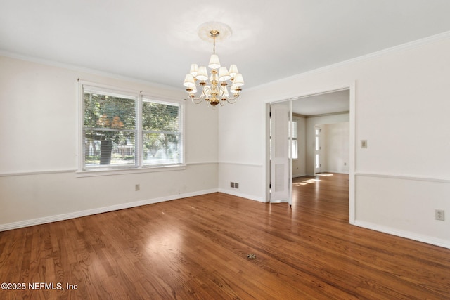 spare room featuring wood finished floors, visible vents, baseboards, ornamental molding, and an inviting chandelier