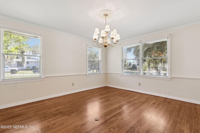 unfurnished room with ornamental molding, a chandelier, baseboards, and wood finished floors