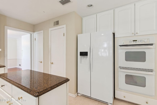 kitchen with white appliances, dark stone countertops, visible vents, and white cabinetry