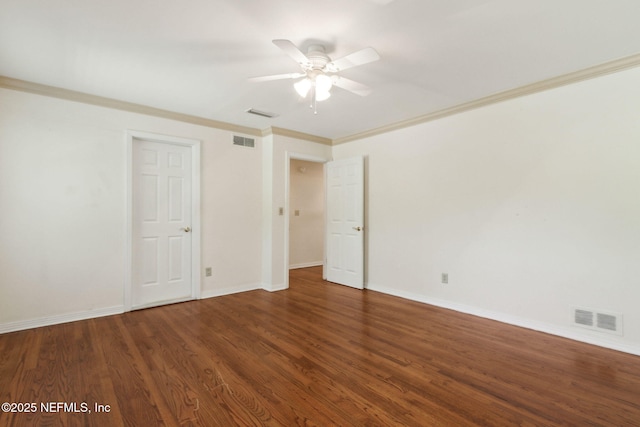 unfurnished room with visible vents, crown molding, baseboards, and wood finished floors