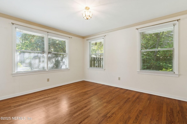 empty room with ornamental molding, baseboards, and wood finished floors