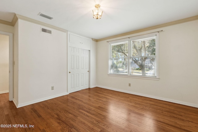 unfurnished bedroom featuring baseboards, crown molding, visible vents, and wood finished floors