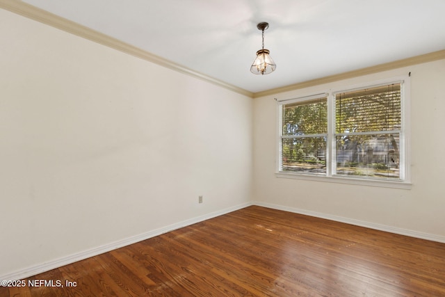 spare room with crown molding, baseboards, and wood finished floors