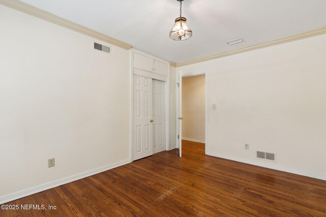 spare room with baseboards, visible vents, and wood finished floors