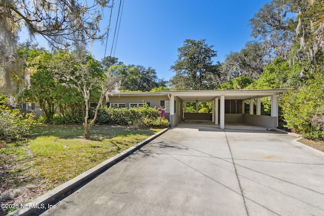 view of front facade with an attached carport, a front lawn, concrete driveway, and stucco siding