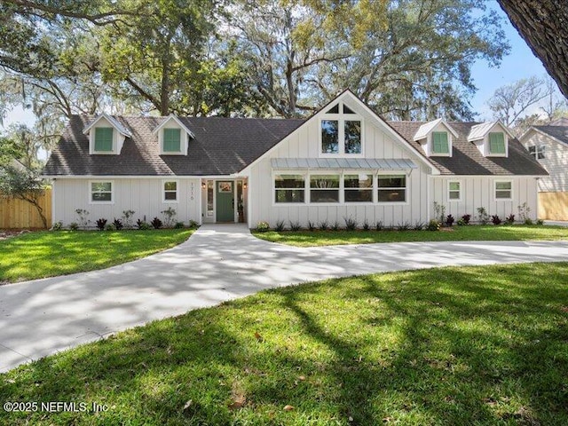 view of front of home featuring fence, driveway, roof with shingles, a front lawn, and board and batten siding