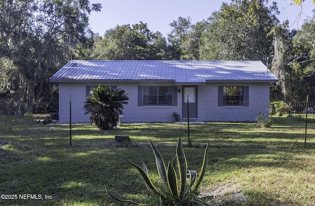 single story home featuring metal roof, central air condition unit, concrete block siding, and a front lawn