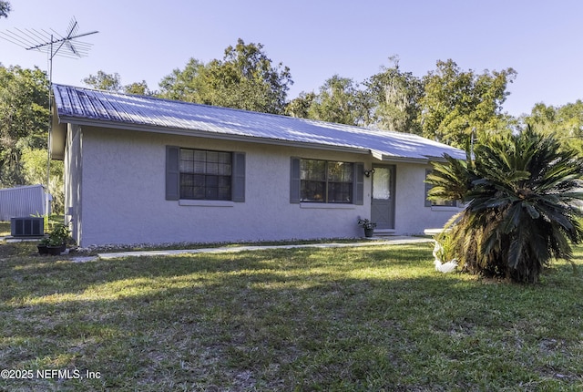 single story home with metal roof, central AC, a front yard, and stucco siding