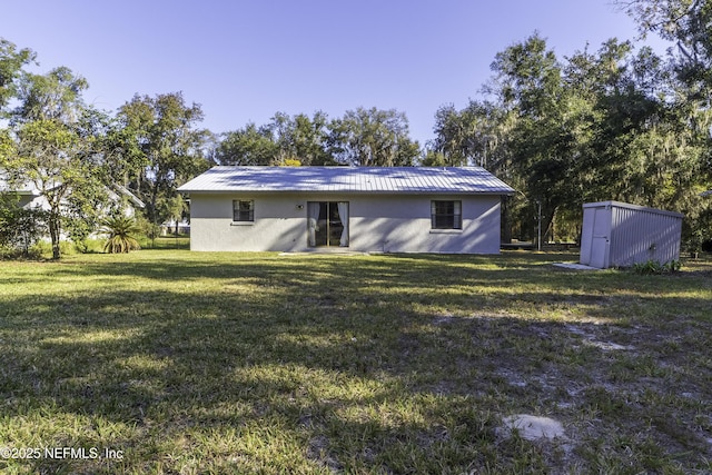 rear view of property featuring stucco siding, a lawn, a storage shed, and an outdoor structure