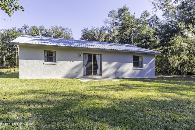 back of house with a yard, metal roof, and stucco siding