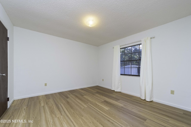 spare room with a textured ceiling, baseboards, and wood finished floors