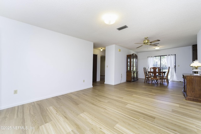 unfurnished living room with visible vents, light wood-style floors, a ceiling fan, and a textured ceiling