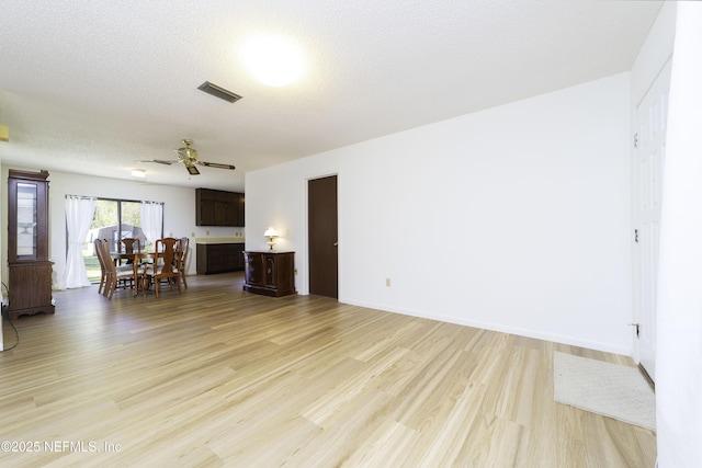 unfurnished living room featuring visible vents, a textured ceiling, a ceiling fan, and light wood finished floors