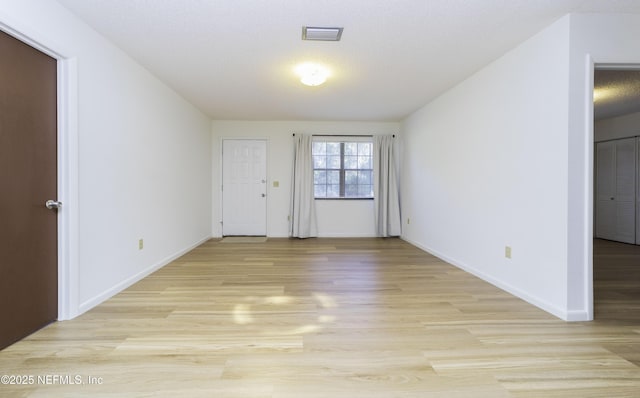 unfurnished room with visible vents, light wood-type flooring, and baseboards